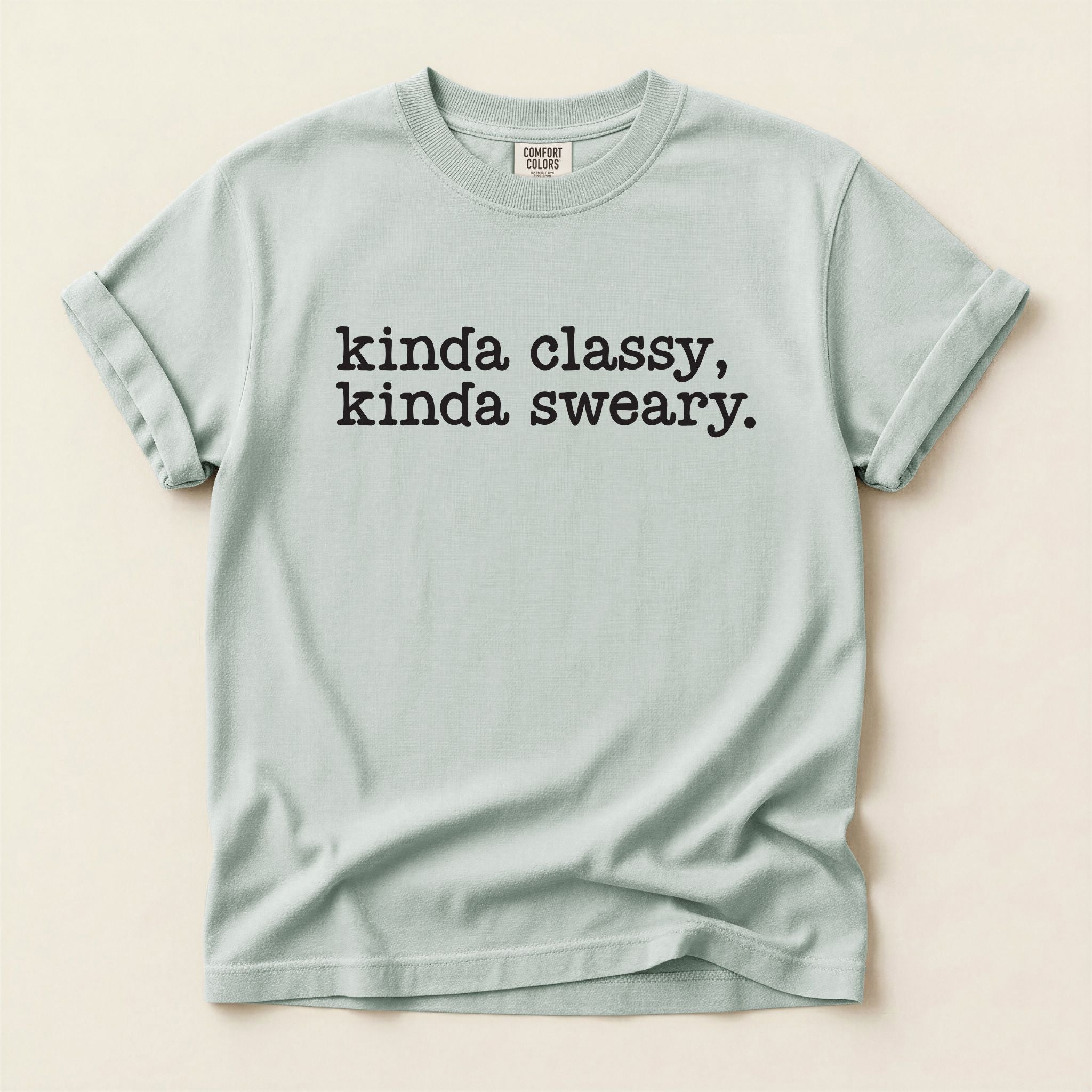 Light blue t-shirt with text 'kinda classy, kinda sweary' on a beige background
