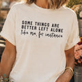 White t-shirt with humorous text worn by a person, with a blurred background.