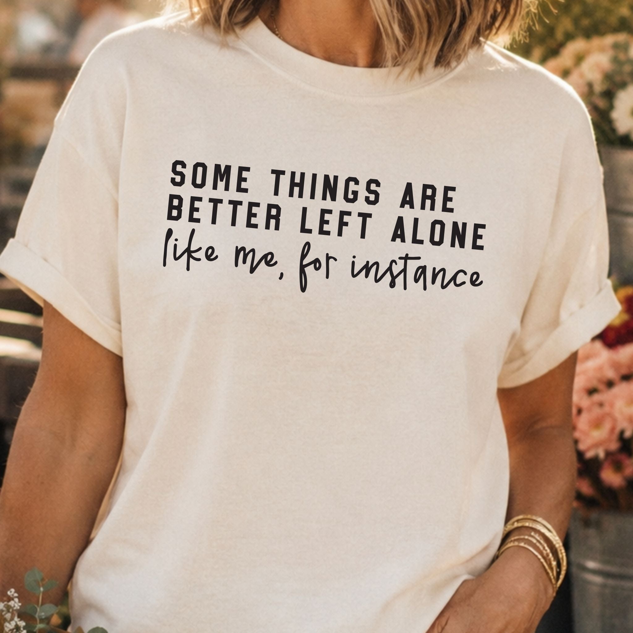 White t-shirt with humorous text worn by a person, with a blurred background.