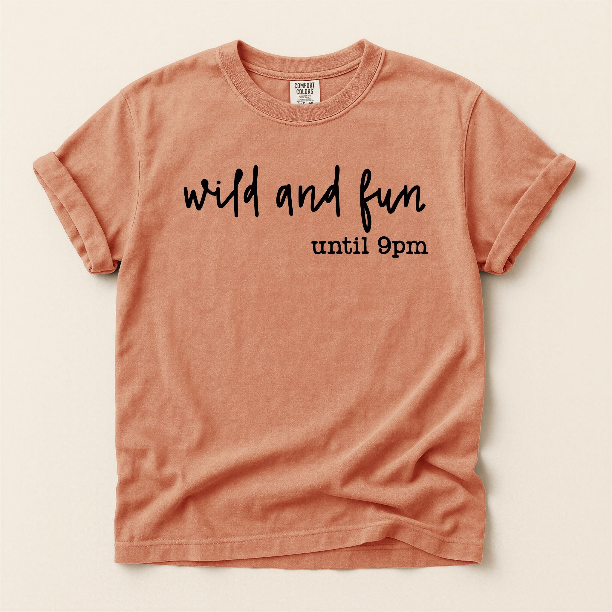 Terracotta colored  t-shirt with 'wild and fun until 9pm' text on a beige background